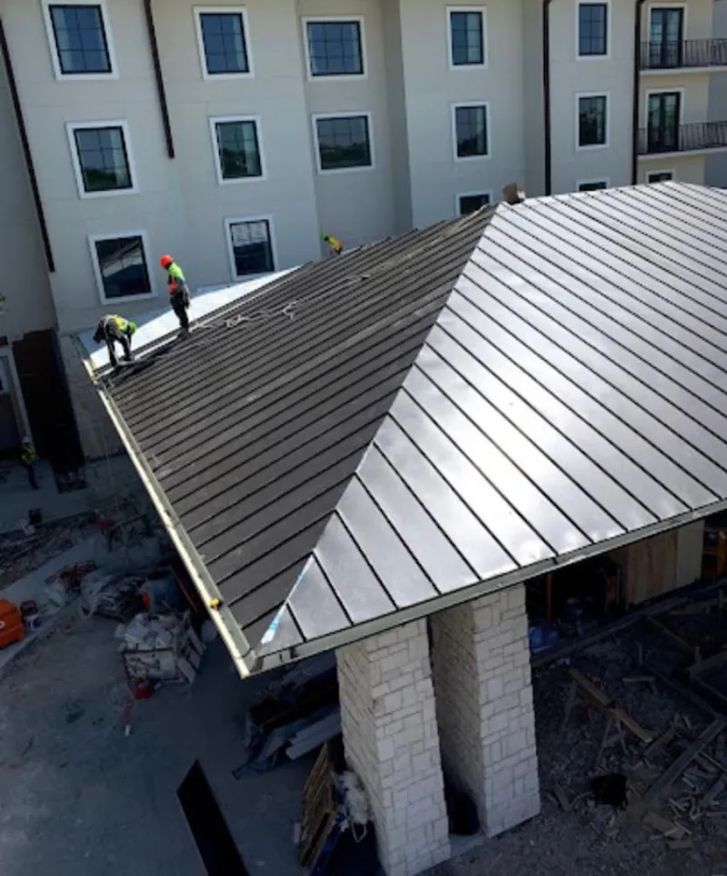 Crew installing standing seam metal roof panels on a commercial project in LaFayette